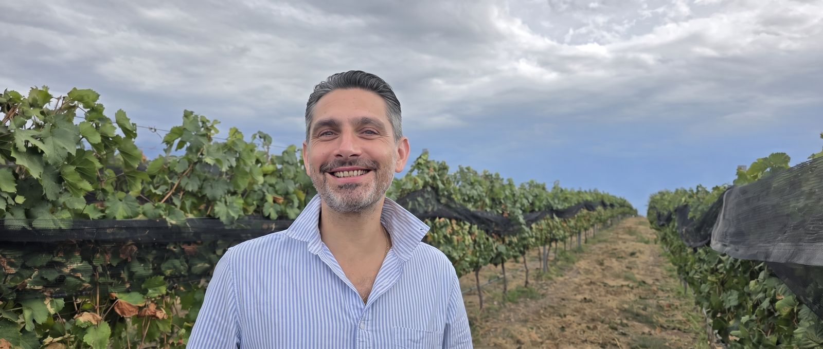 Louis-Vincent Manoukian dans les vignes, sous un ciel nuageux.